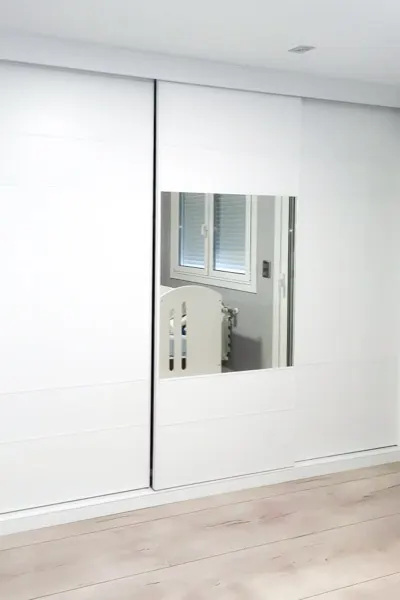 Armario empotrado lacado en blanco con puertas correderas y espejo